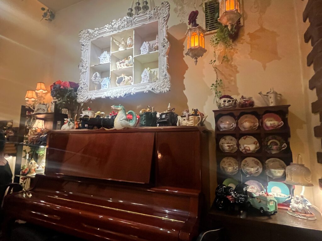 店内の壁際にアンティークのピアノとティーカップが飾られている。