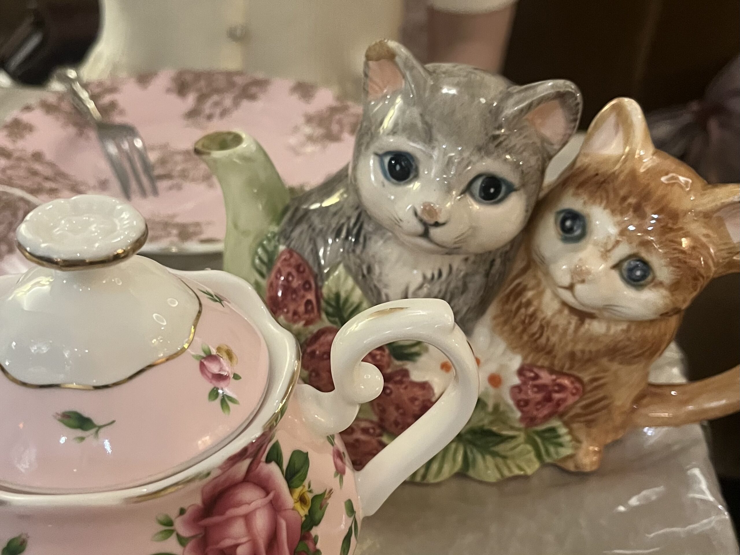 猫の形をしたティーポットと花柄のティーポットがテーブルのうえに置かれている。