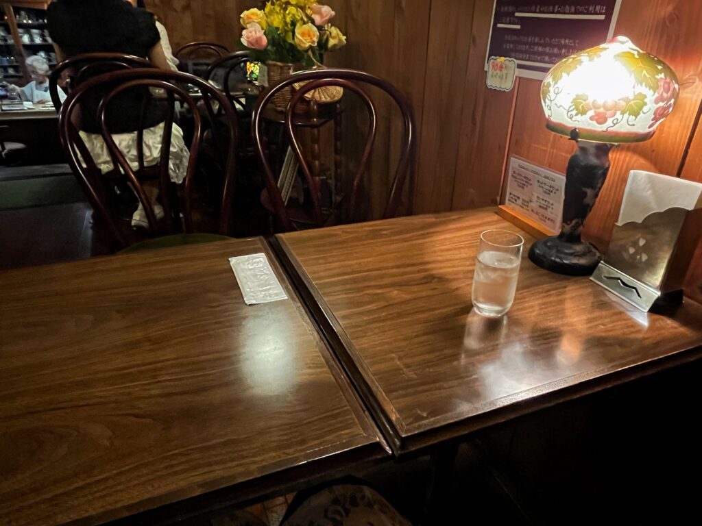 ランプが飾られた木製のテーブルが並ぶ、れとろでおりついた喫茶店の店内