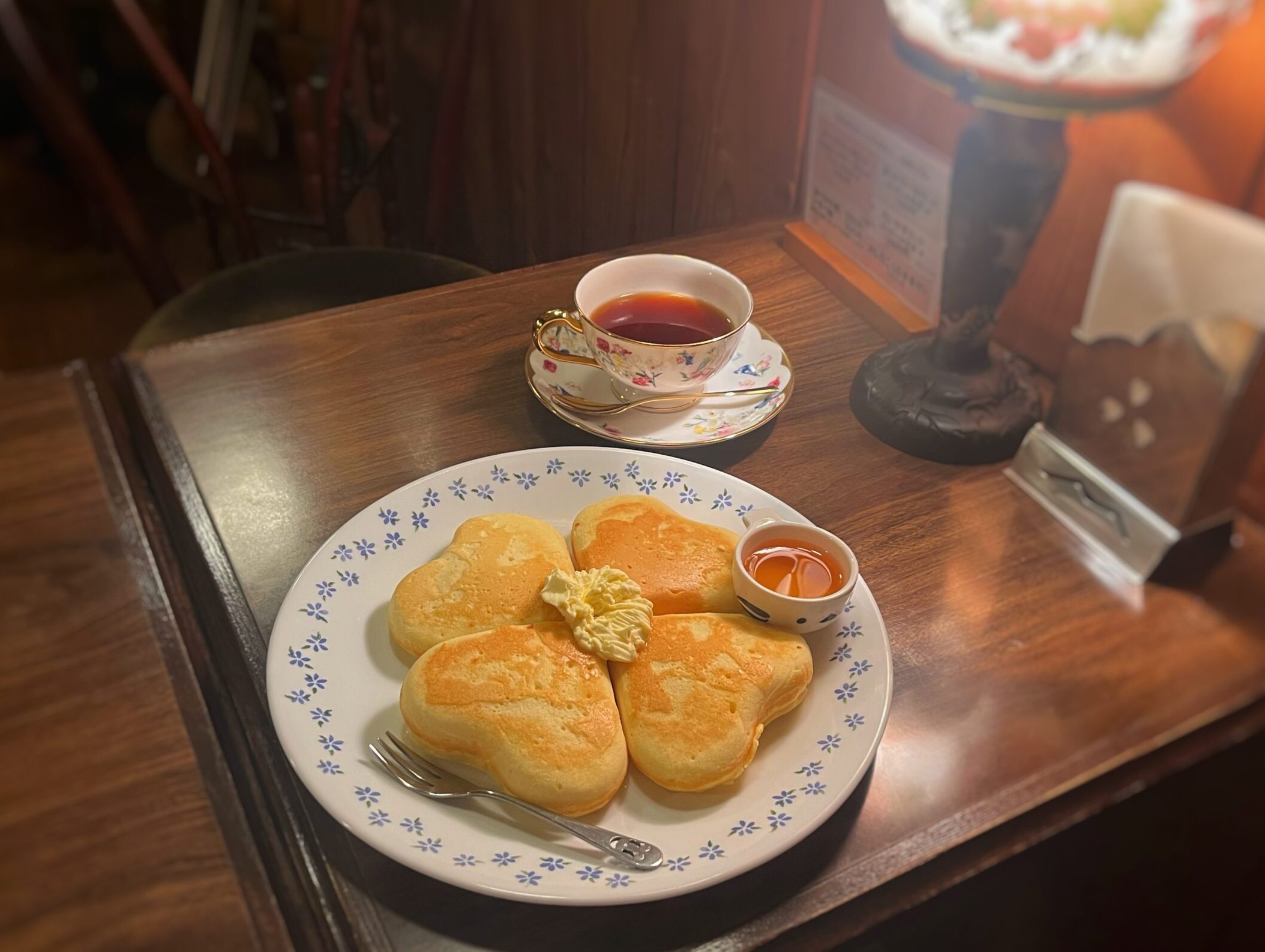木製のテーブルの上にクローバー型のホットケーキとカップに入ったコーヒーが並べられている。